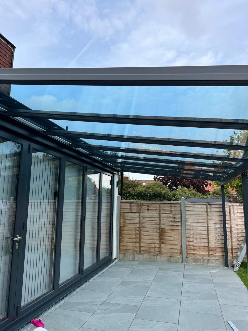 Glass-roofed garden canopy with sky reflections, fitted by Ertan Glass